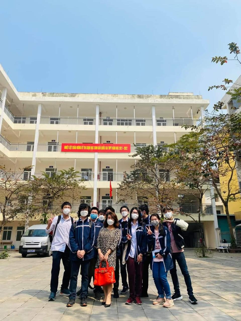 A group of people posing for a photo in front of a building</p> <p>Description automatically generated